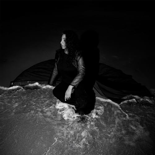 Black and white portrait of Arooj Aftab in water with flowing fabric.