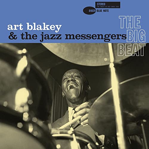 Black and white photo of drummer with blue album title banner across top.