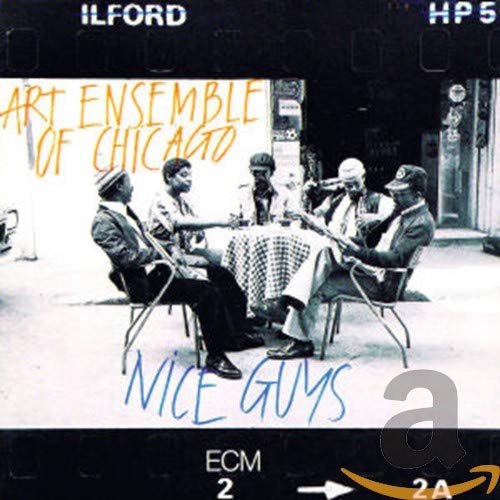 Black and white photo of five musicians seated around a table.