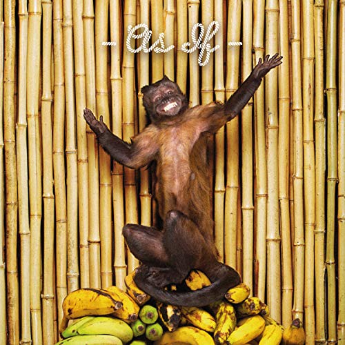 Monkey in front of bamboo with a pile of bananas.