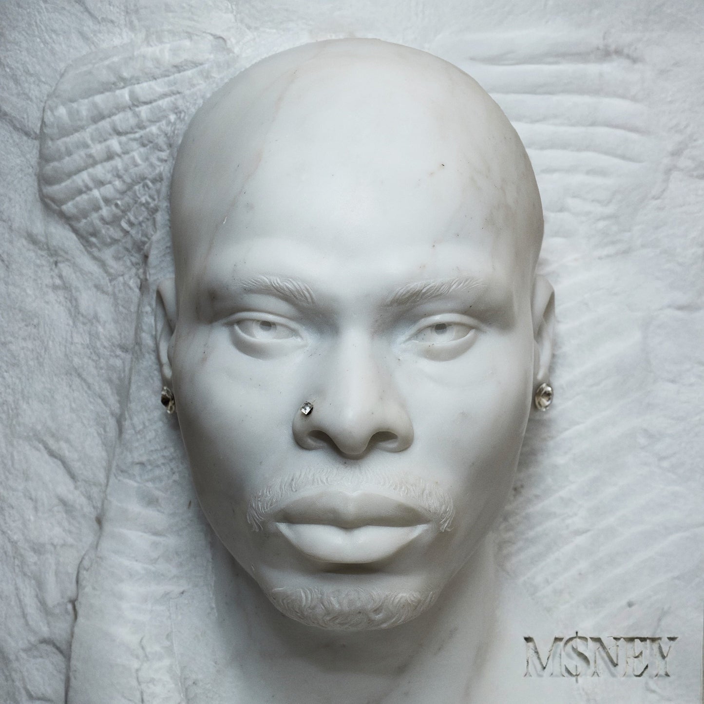 White marble sculpture of a man's face with nose and ear studs.