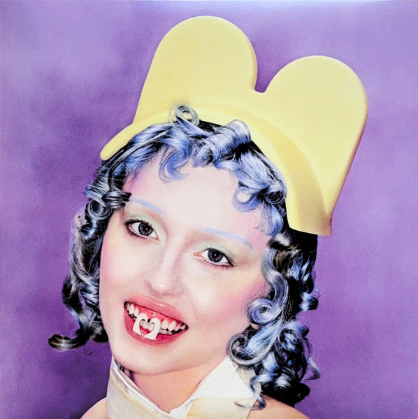 Ashnikko with blue curly hair and yellow Minnie Mouse ears.