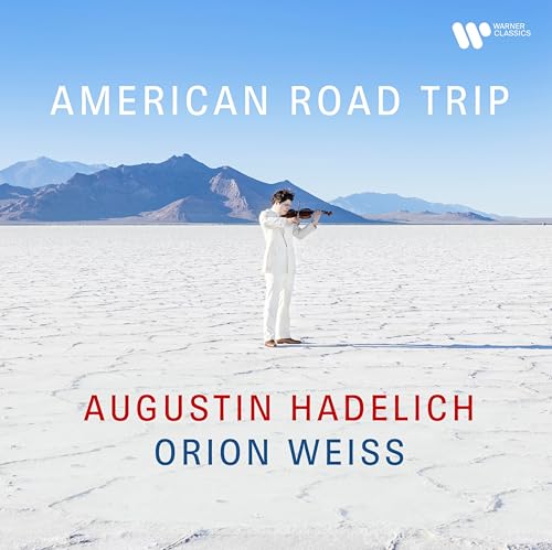 Violinist Augustin Hadelich in a white suit stands on a salt flat landscape.
