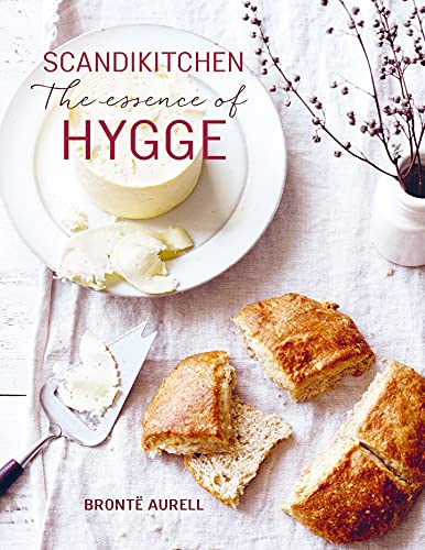 Cookbook cover with cheese, scones, and a sprig of berries on linen.