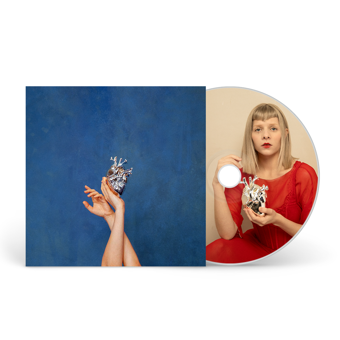 CD cover featuring hands holding a metallic heart against blue, with disc showing Aurora.