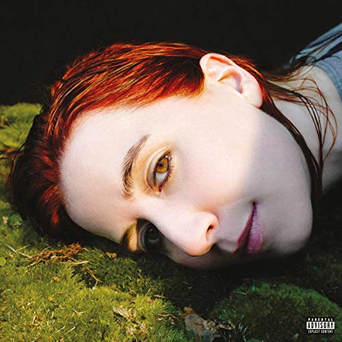 Close-up of a woman with red hair lying on green moss.