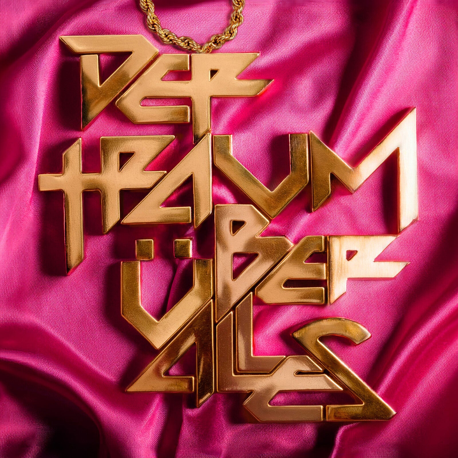 Gold lettering spelling "Der Traum Uber Alles" on pink satin fabric.