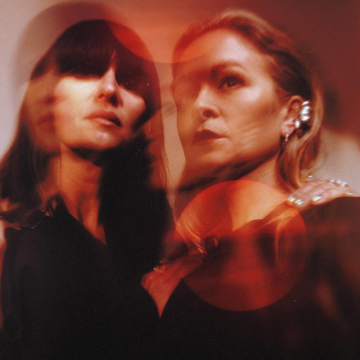 Double exposure portrait of two women in warm red tones with a grainy texture.