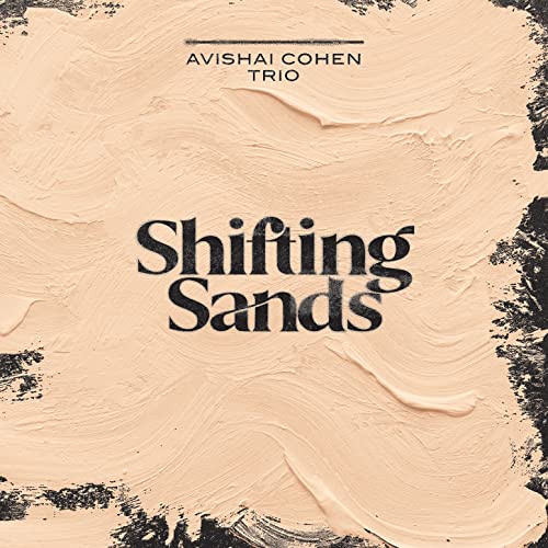 Album cover with thick beige paint strokes over black, featuring Avishai Cohen Trio Shifting Sands.