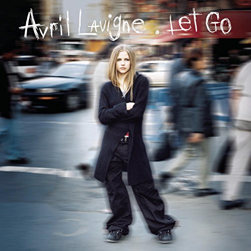 Avril Lavigne stands in a busy street with blurred motion in the background.