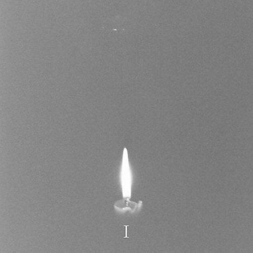 Black and white image of a single lit candle flame with the letter "I".