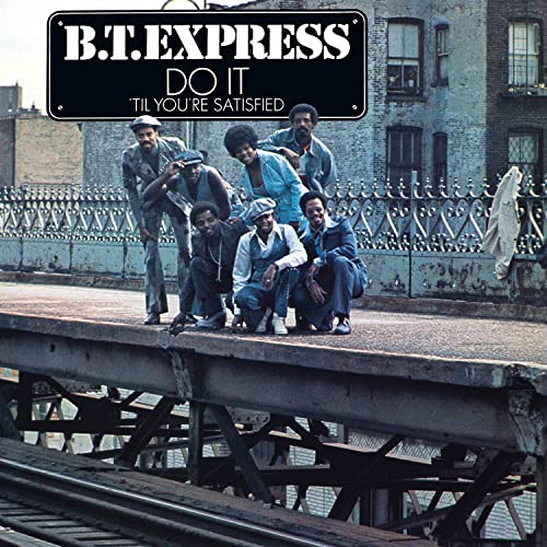 The band B.T. Express poses on an elevated train platform in this album cover.