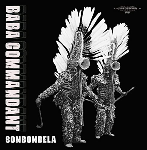Two figures in traditional feathered costumes and masks stand against a black background.