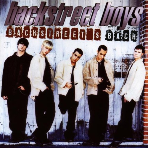 The five members of the Backstreet Boys stand against a white wooden wall.