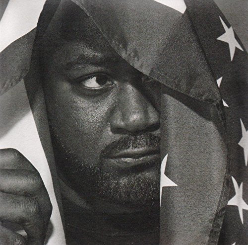 Black and white portrait of Ghostface Killah partially obscured by a US flag.