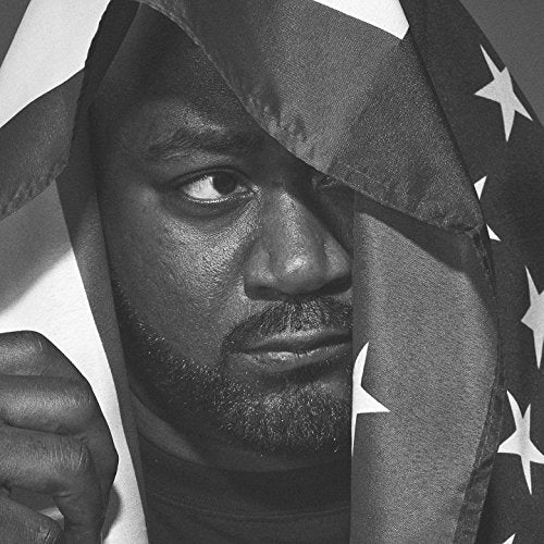 Black and white portrait of Ghostface Killa partially obscured by an American flag.