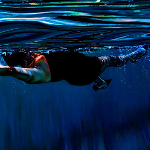 Underwater view of a person swimming with patterned legs and feet.