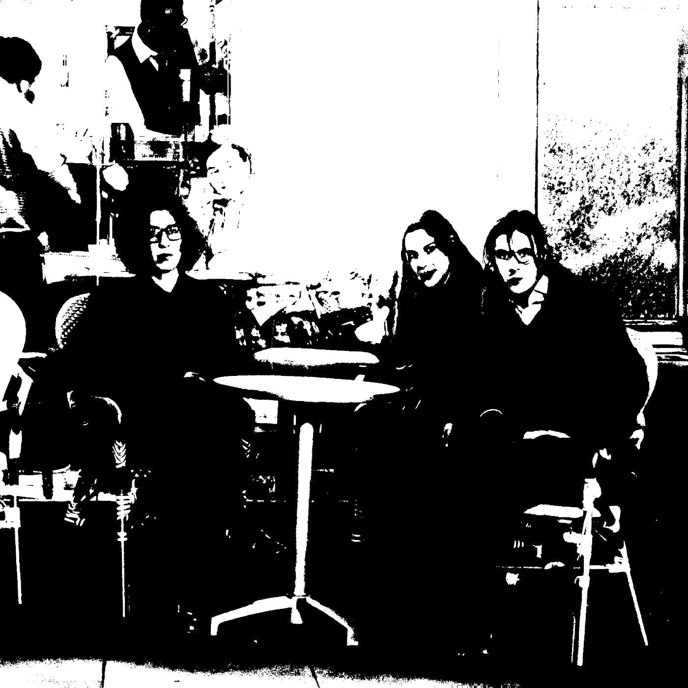 Black and white photo of three people seated around a table.