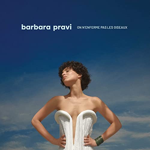 Barbara Pravi against a blue sky, wearing a white fringed strapless top.