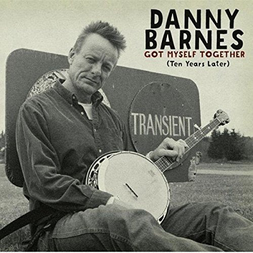 "CD cover with man holding banjo, sitting by a 'transient' sign."