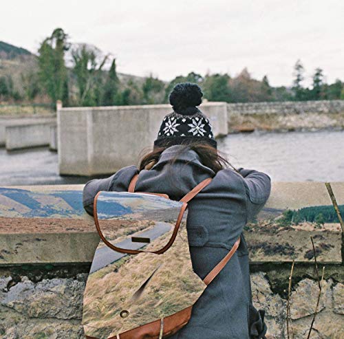 Person with backpack looking at a waterway and distant hills.