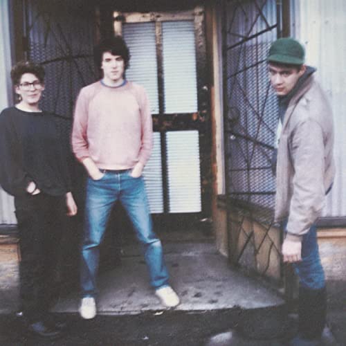 Beat Happening band portrait: three people in front of a metal gate.