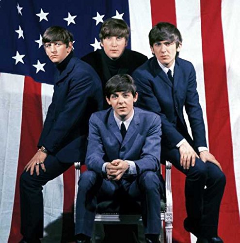 The Beatles band members posing in front of an American flag.