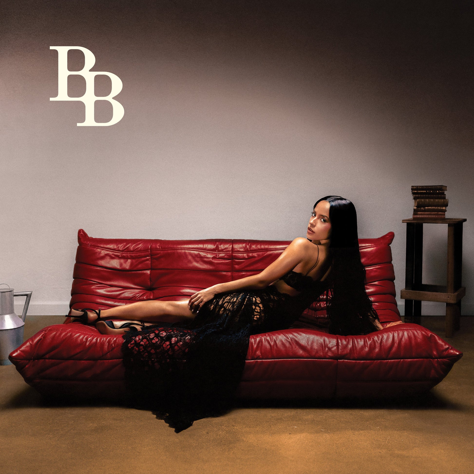 Becky G reclines on a red leather couch for the “Baraja Bendita” vinyl album cover.