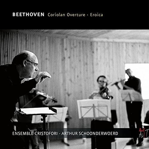 Black and white photo of a conductor with musicians rehearsing.