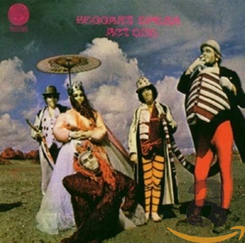 Five costumed figures in a surreal landscape under a cloudy blue sky.
