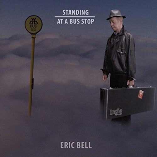 CD cover: man with guitar case at a bus stop, cloudy sky.