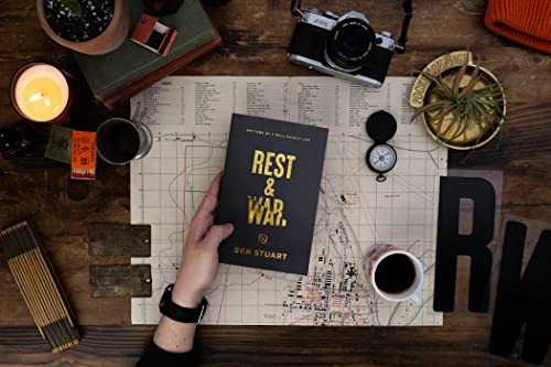Book "Rest & War" held over a map with coffee and plants.