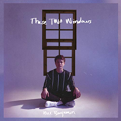 Man sitting cross-legged in front of a window, on a purple album cover.