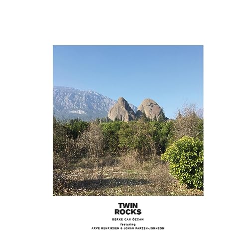 Landscape photograph of rock formations with trees, album cover art.