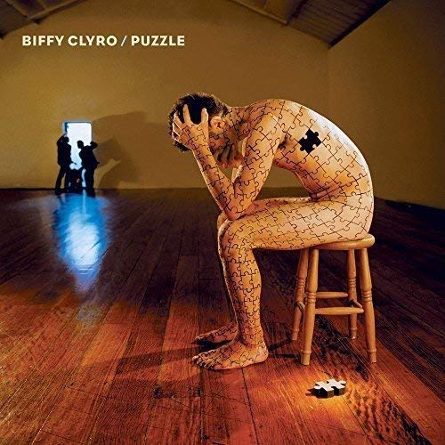 Man composed of puzzle pieces sits dejected in a wooden room.