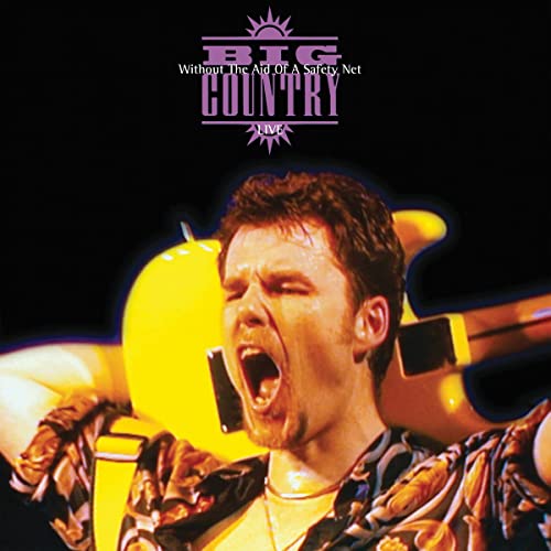 A man singing passionately with a yellow electric guitar behind him on stage.