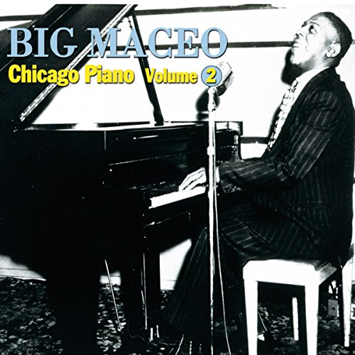 Black and white image of man in suit playing piano and singing into a microphone.