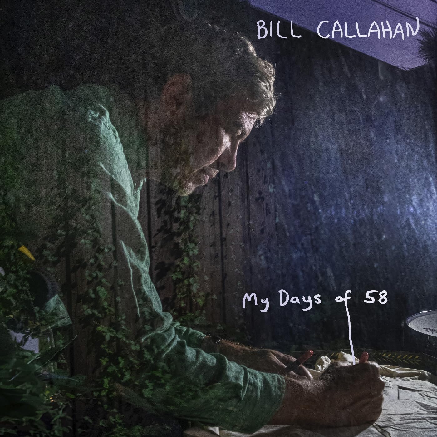 Double exposure image of Bill Callahan writing at a table with foliage overlay.