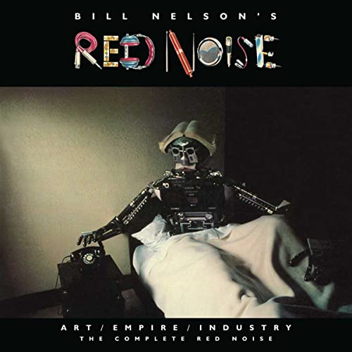 A robot wearing a hat sits in bed next to a telephone.