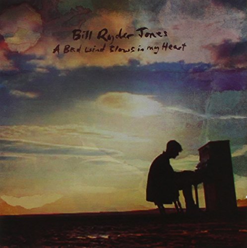 Album cover with a man playing piano at sunset in a desert landscape.