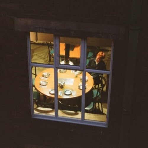 People seated around a table viewed through a window at night.