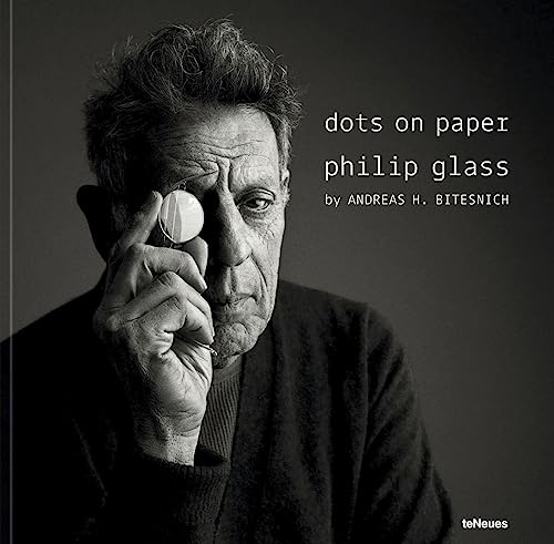 Black and white portrait of composer Philip Glass holding a small object.