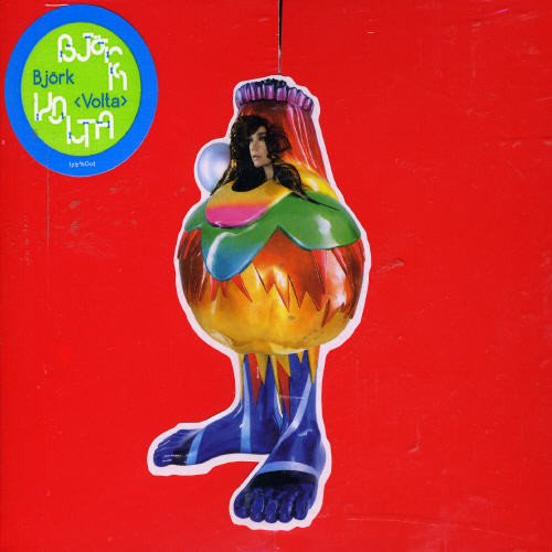 Björk wearing a colorful, abstract costume against a bright red background.
