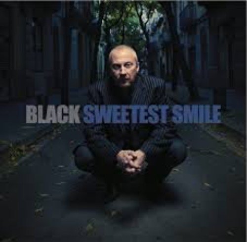 Vinyl album cover featuring a man in a suit crouching on pavement.