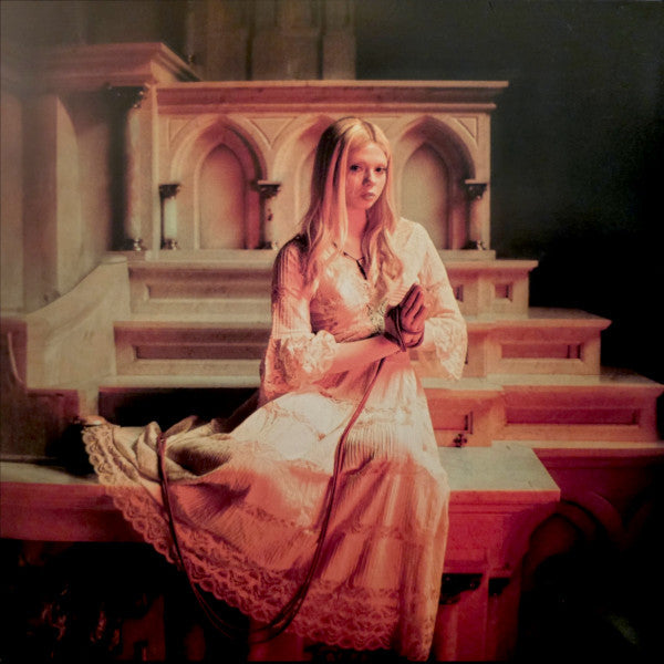 Blond woman in a white lace dress sits on stone steps.
