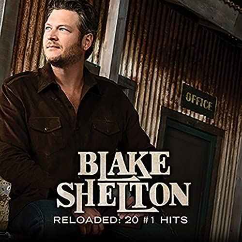 Blake Shelton wearing a brown shirt against a corrugated metal wall with office sign.