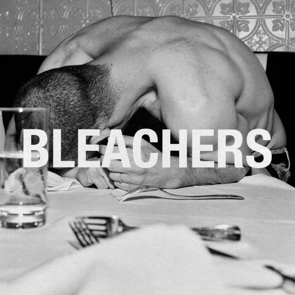Black and white photo of a shirtless man resting his head on a table.