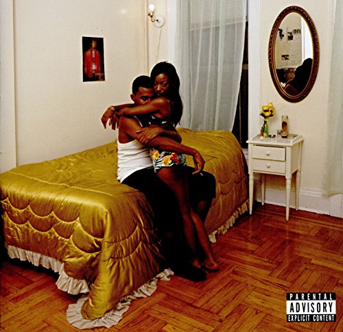 Couple embracing on a gold bed in a room with a mirror.