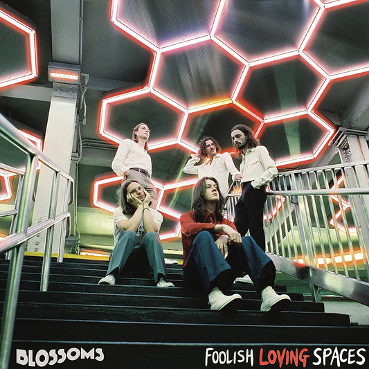 Album cover: five men running up stairs under a honeycomb-patterned ceiling with neon lights.