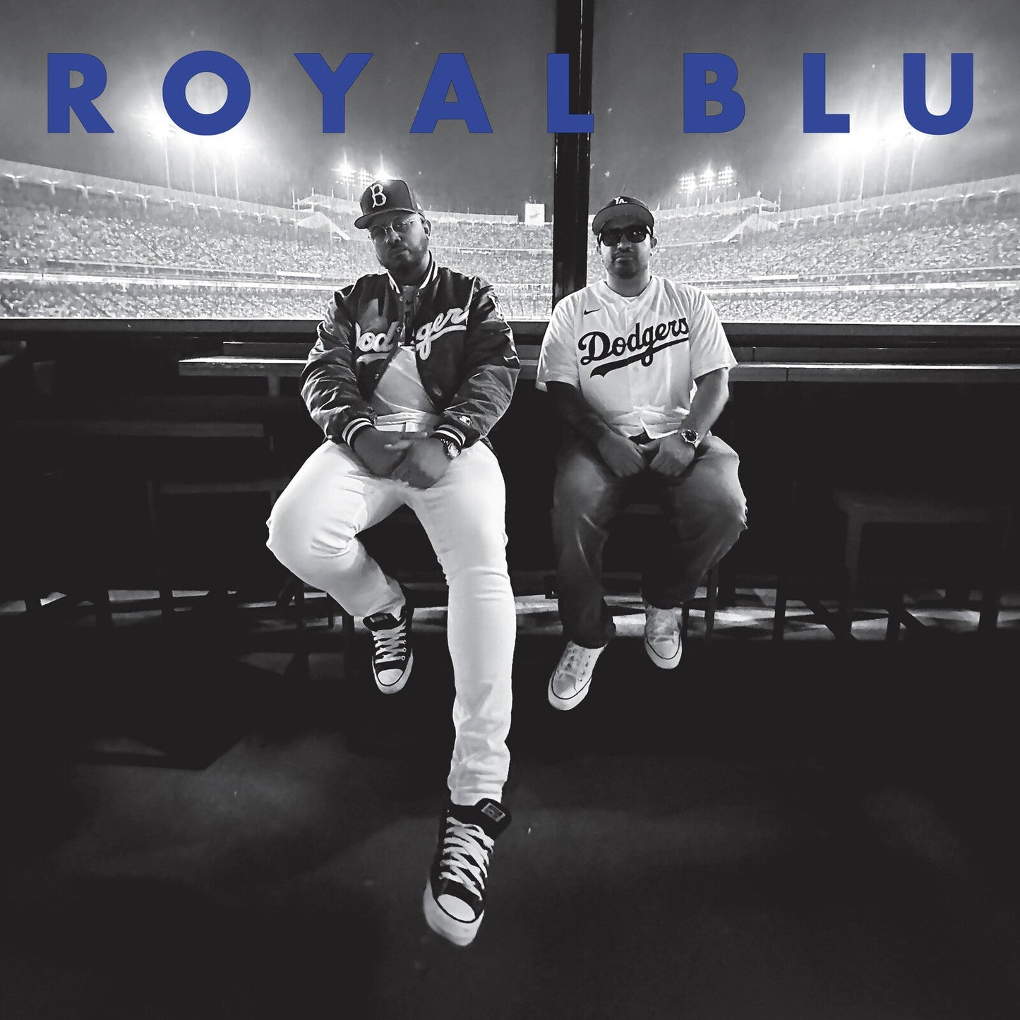 Two men in Dodgers apparel sit before a stadium background with blue text overlay.